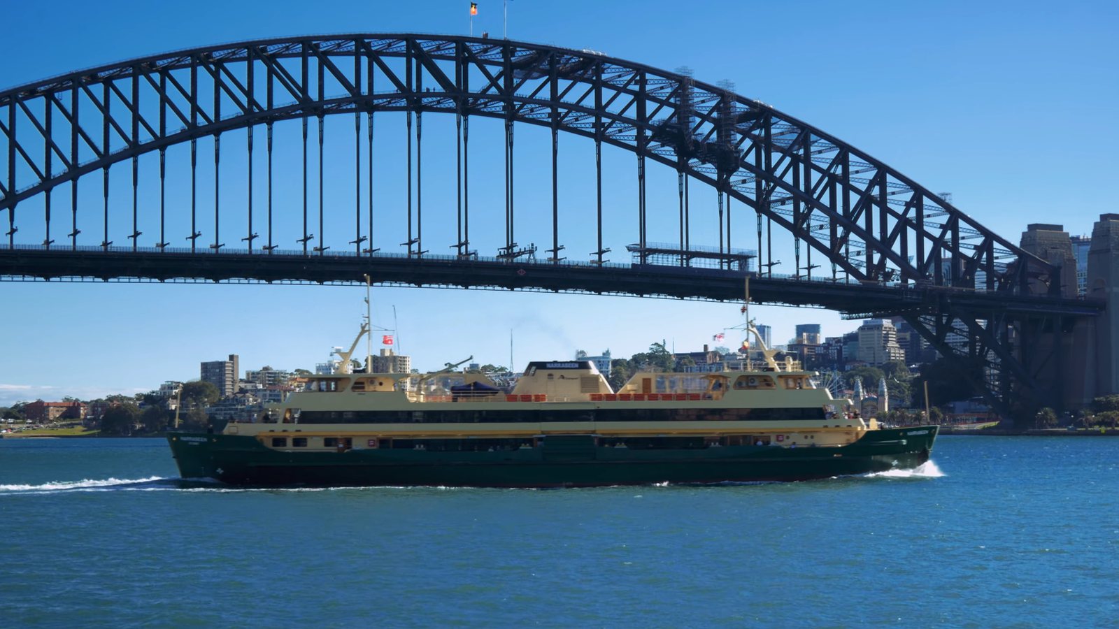 Sydney public ferry crossing the harbour beneath Sydney Harbour Bridge